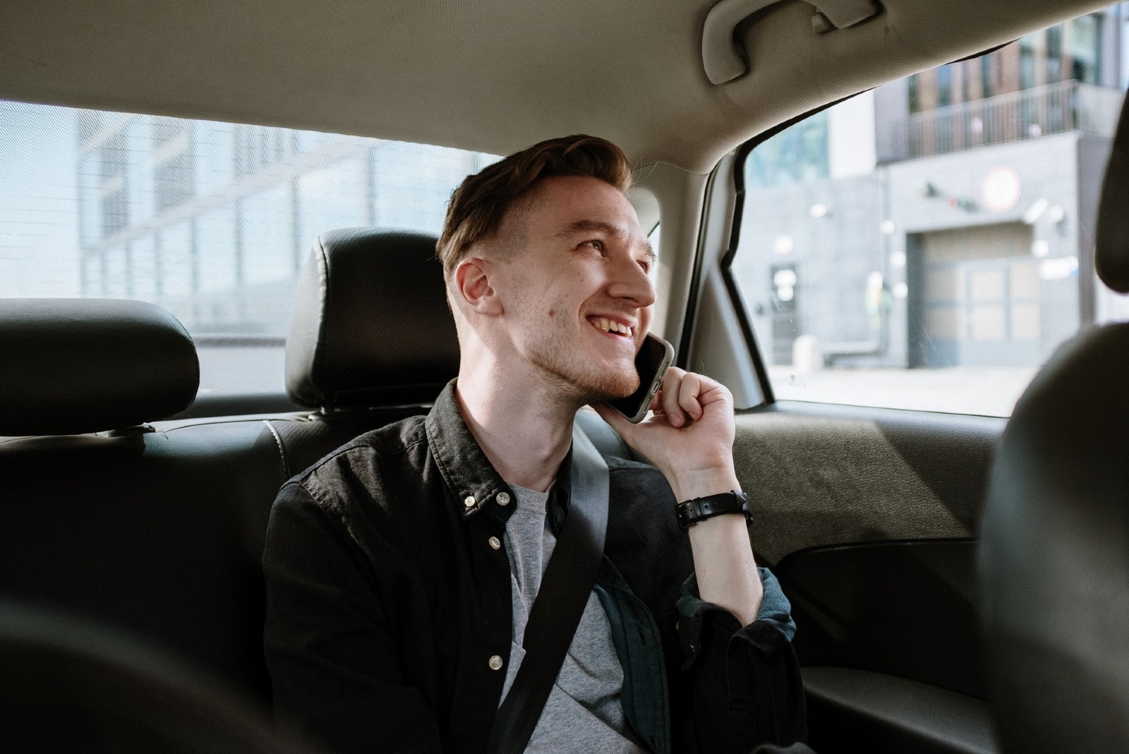 happy man talking on the phone while sitting in car