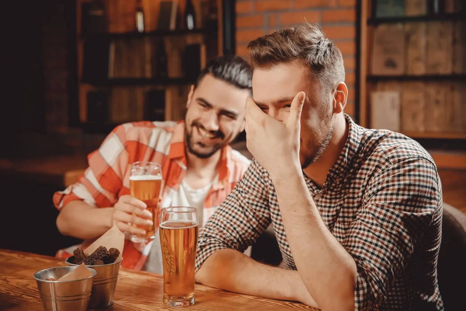 two men laughing while drinking beer