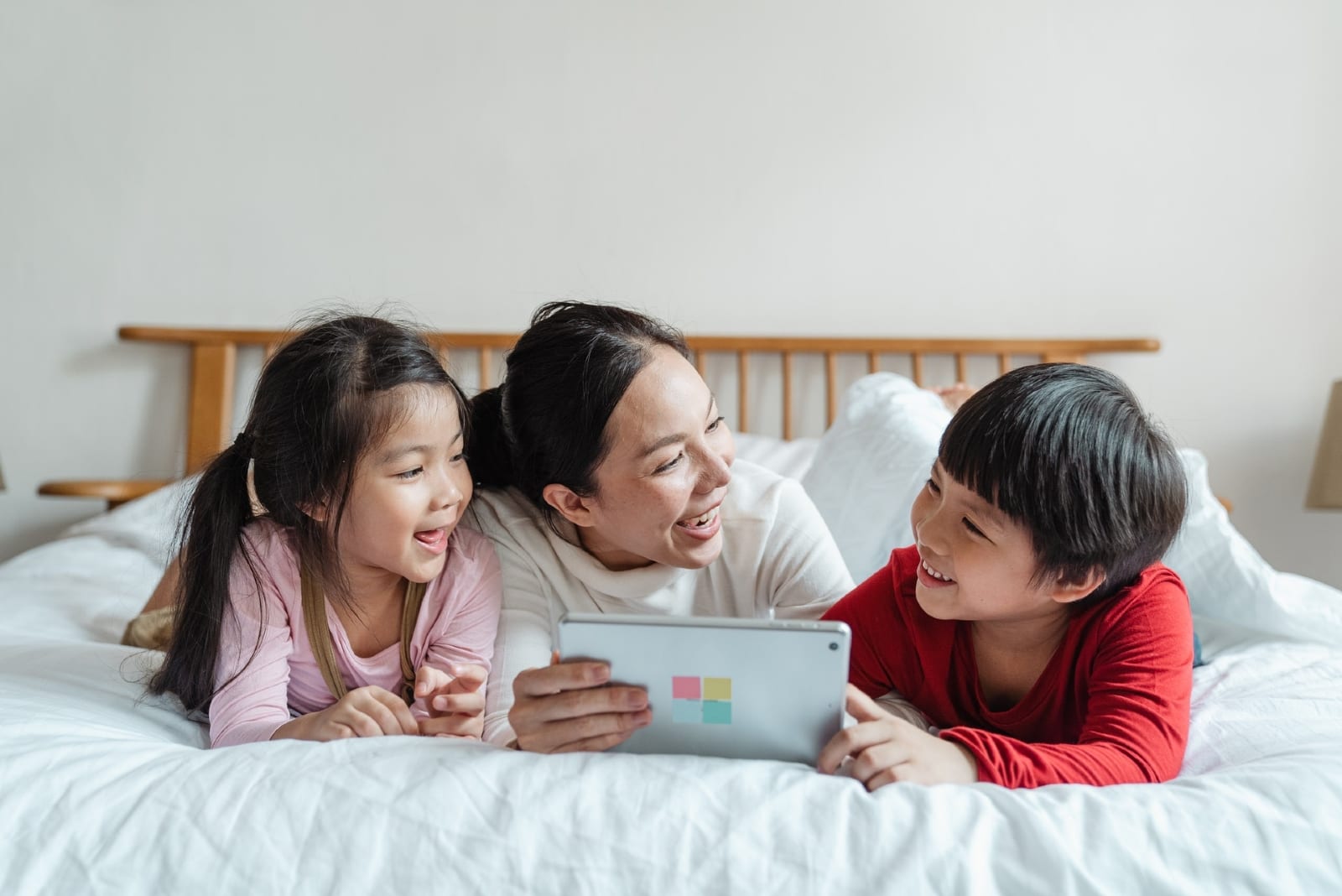 madre e figli che usano il laptop sul letto