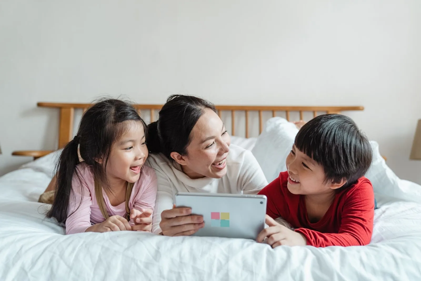 mother and children using laptop on bed