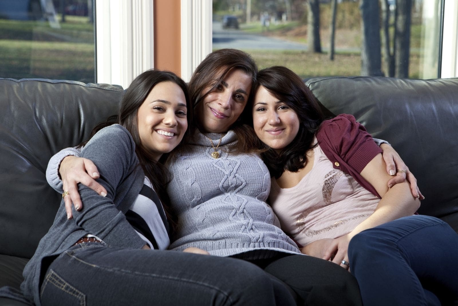 mãe e duas filhas sentadas no sofá da sala de estar