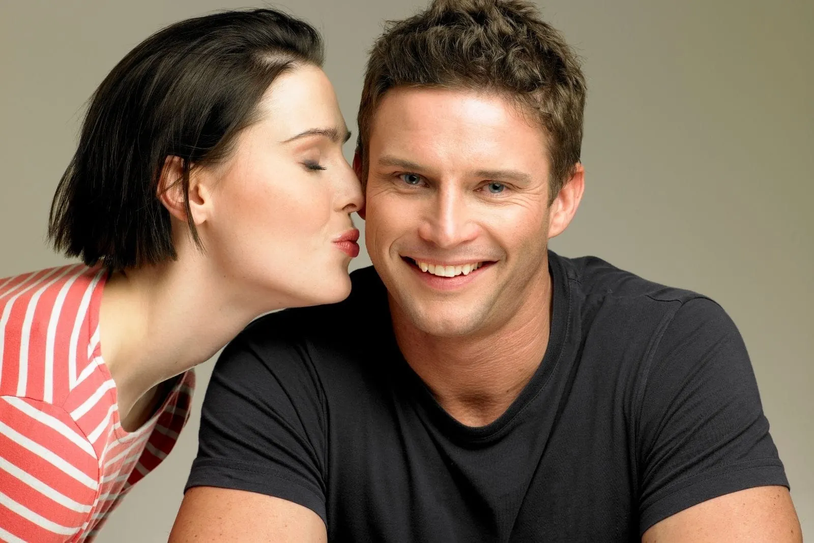 peck on the cheek of the man smiling by a woman