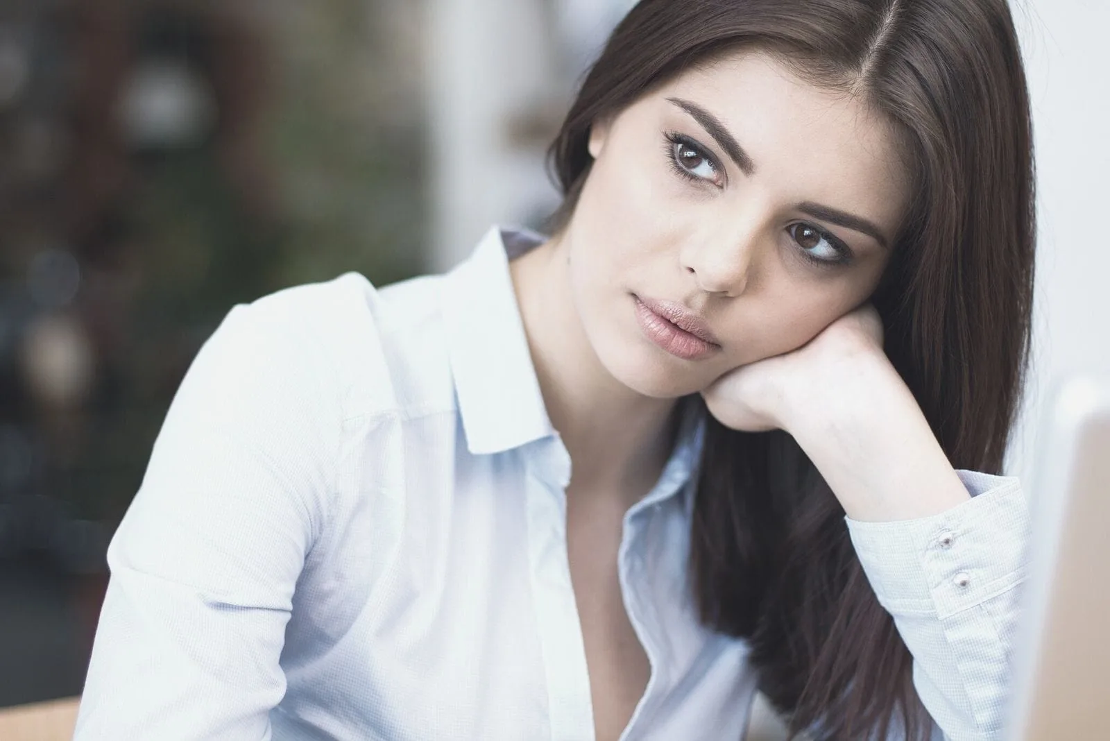 pensive businesswoman looking away and leaning her head to her hand