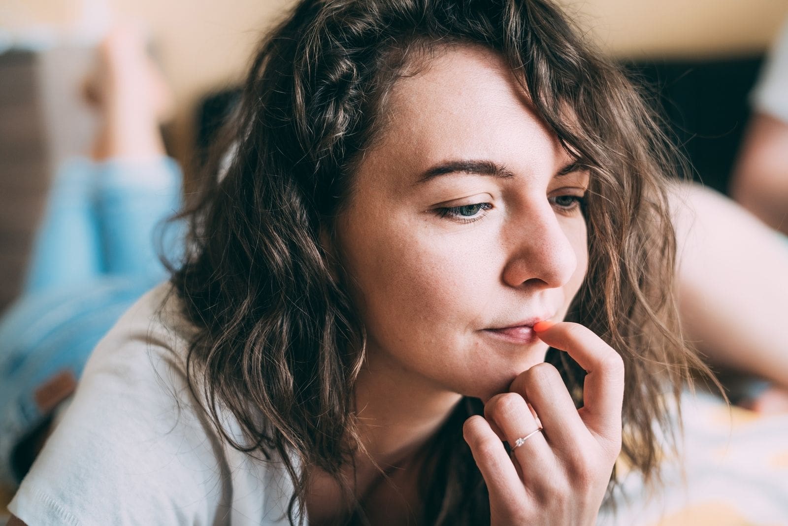 pensive caucasian woman picking thumb on lips with focus on the face