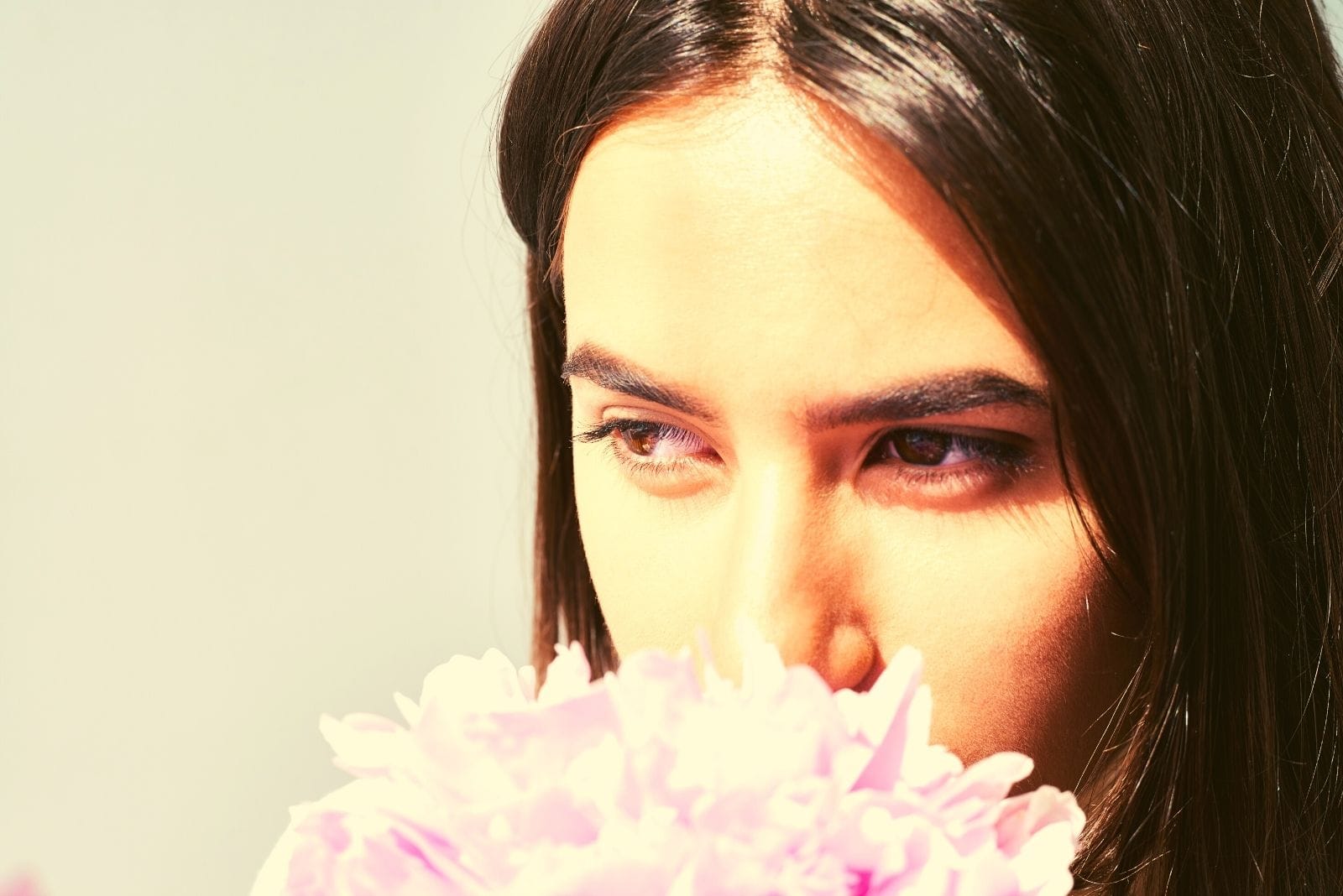 mujer pensativa inhalando aroma de peonia foco en el rostro 