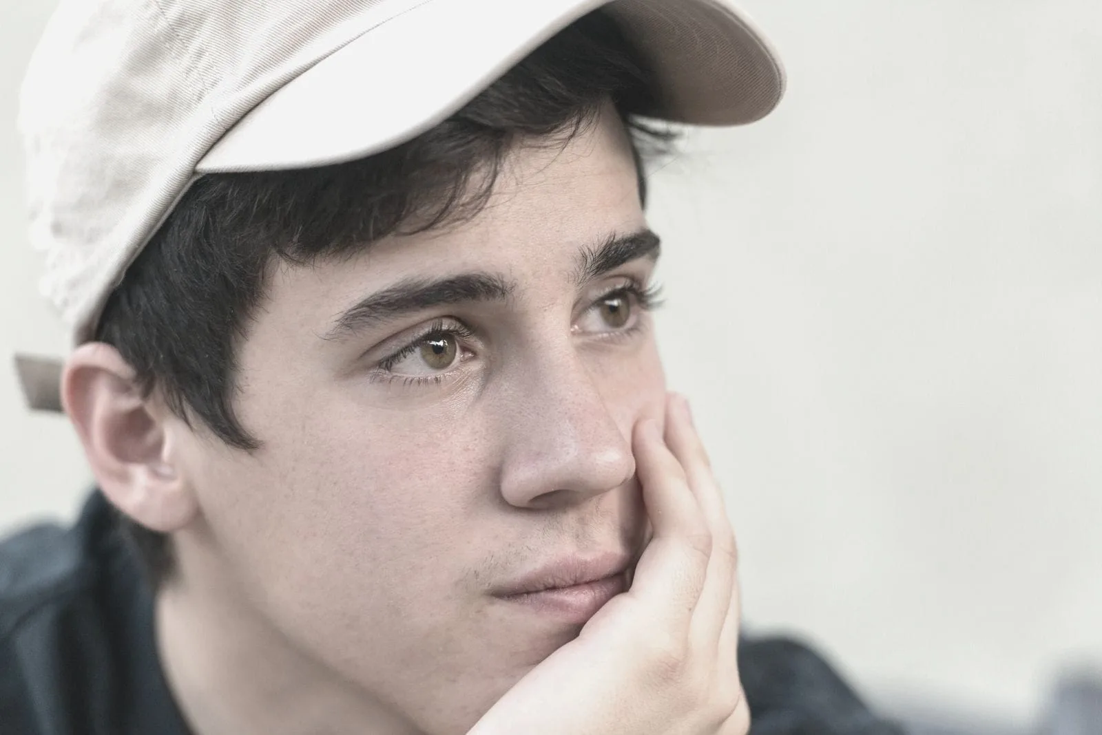pensive young man looking away wearing a cap