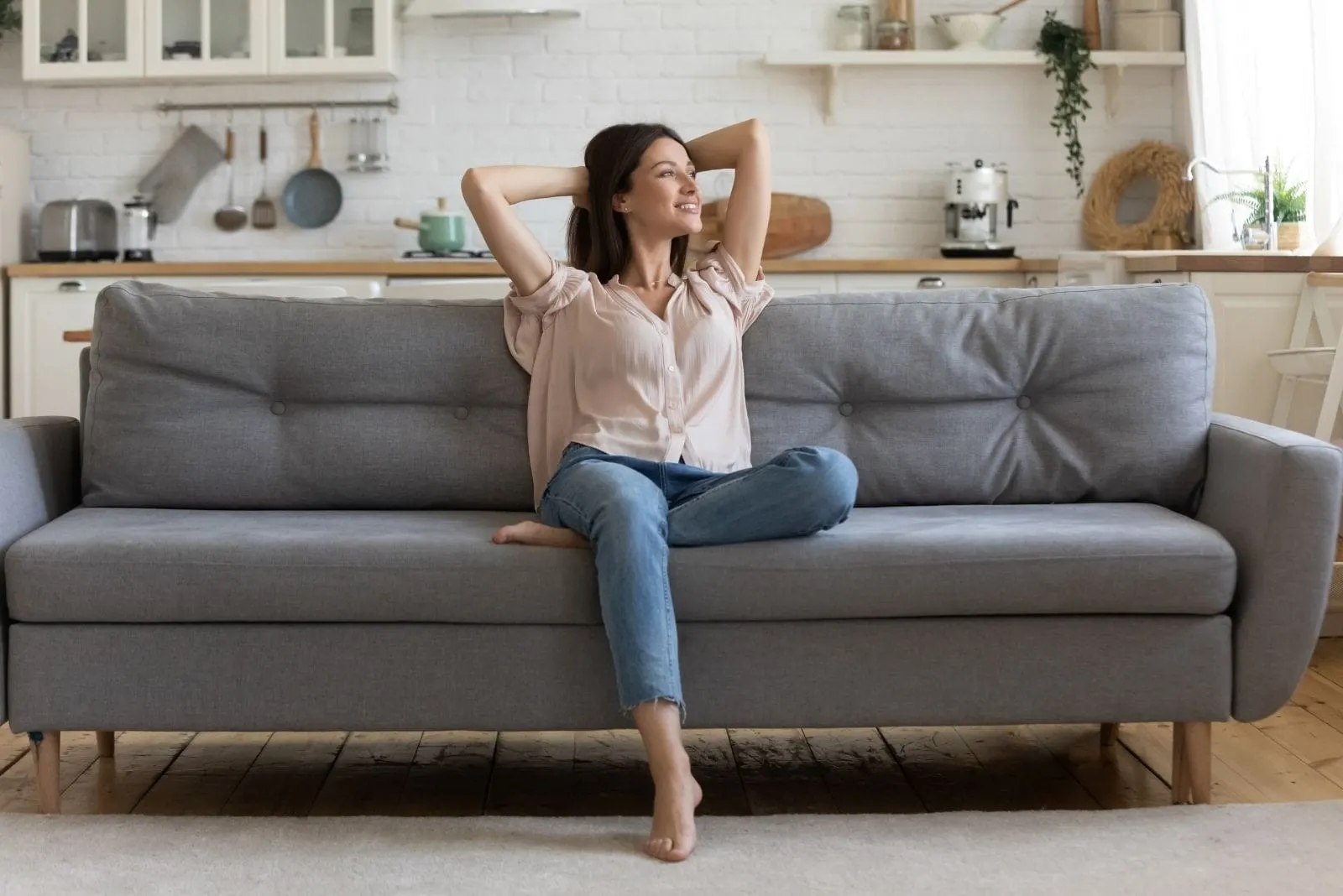 relaxed woman sitting on the gray sofa looking away inside the living room