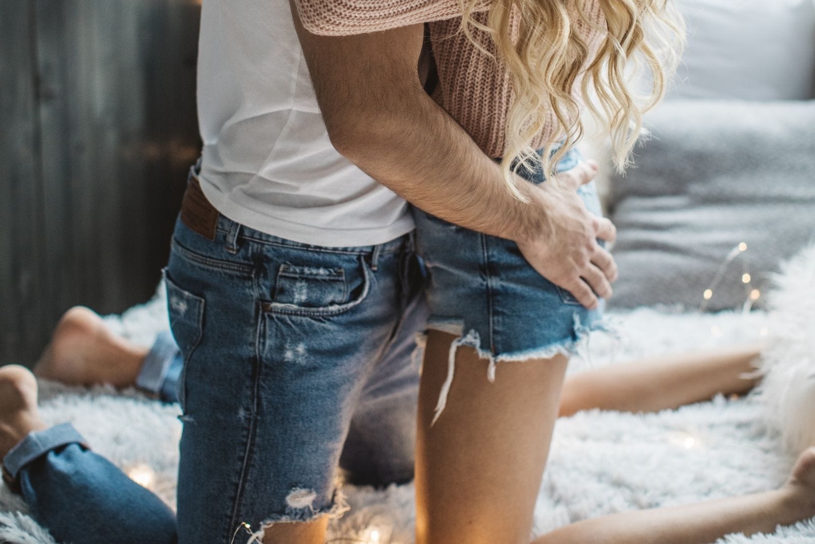 coppia romantica a letto che si bacia con la mano del ragazzo sulla tasca posteriore della donna