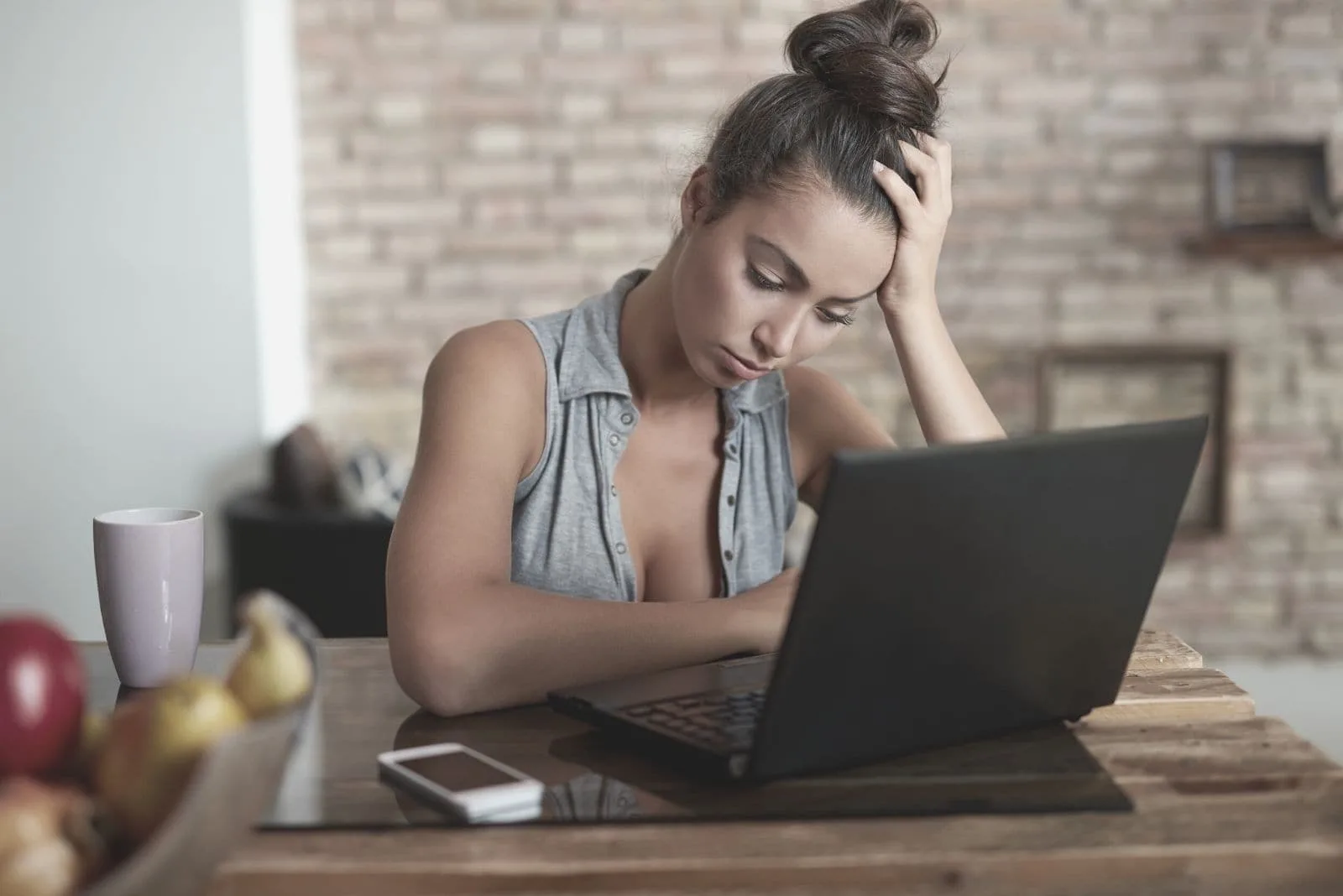 sad woman with a laptop looking down and sitting inside her home office