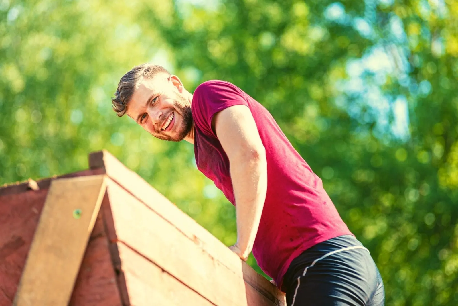 smiling man climbing over the obstacle at and extreme race at boot camp
