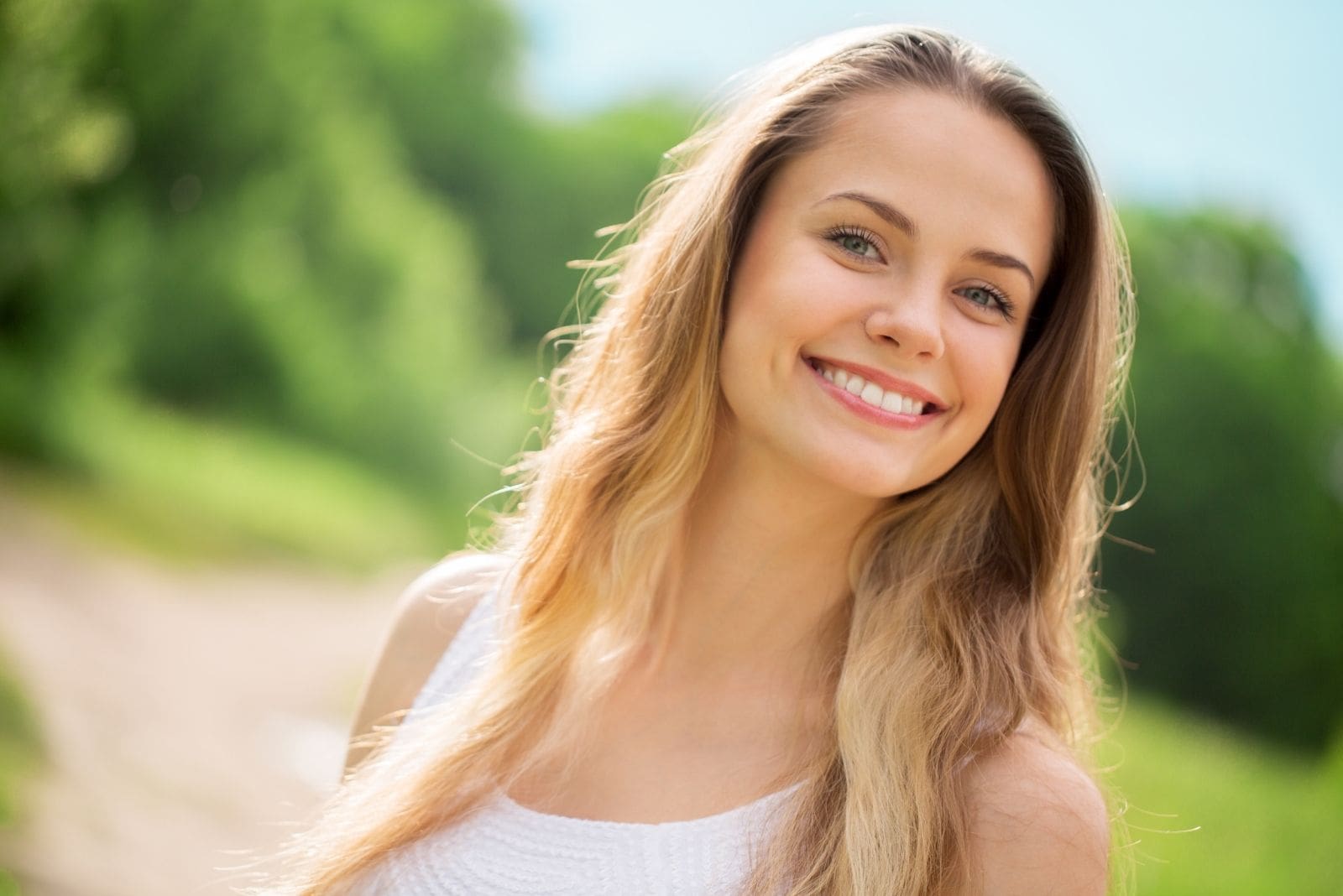 smiling woman outdoors wearing simple white top