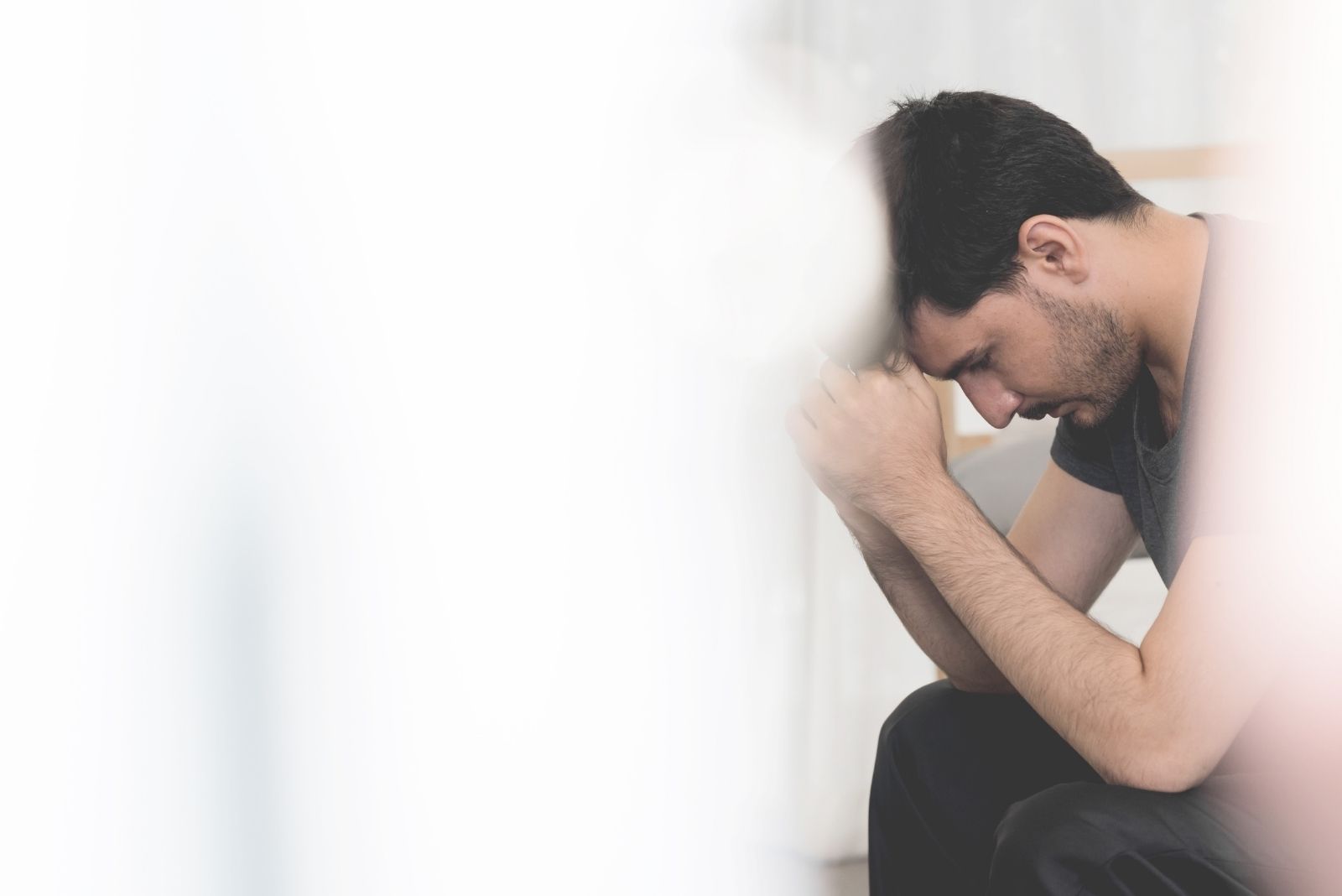 homem stressado e triste sentado com a imagem parcialmente coberta por uma coisa branca