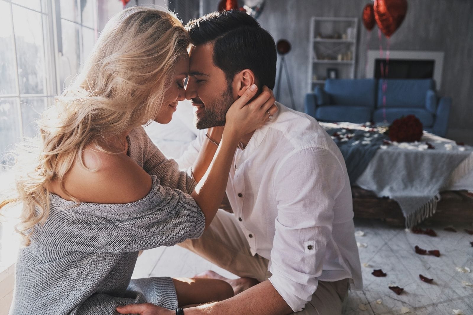 dulce pareja celebrando el amor o la luna de miel en el interior de la habitación llena de corazones y globos