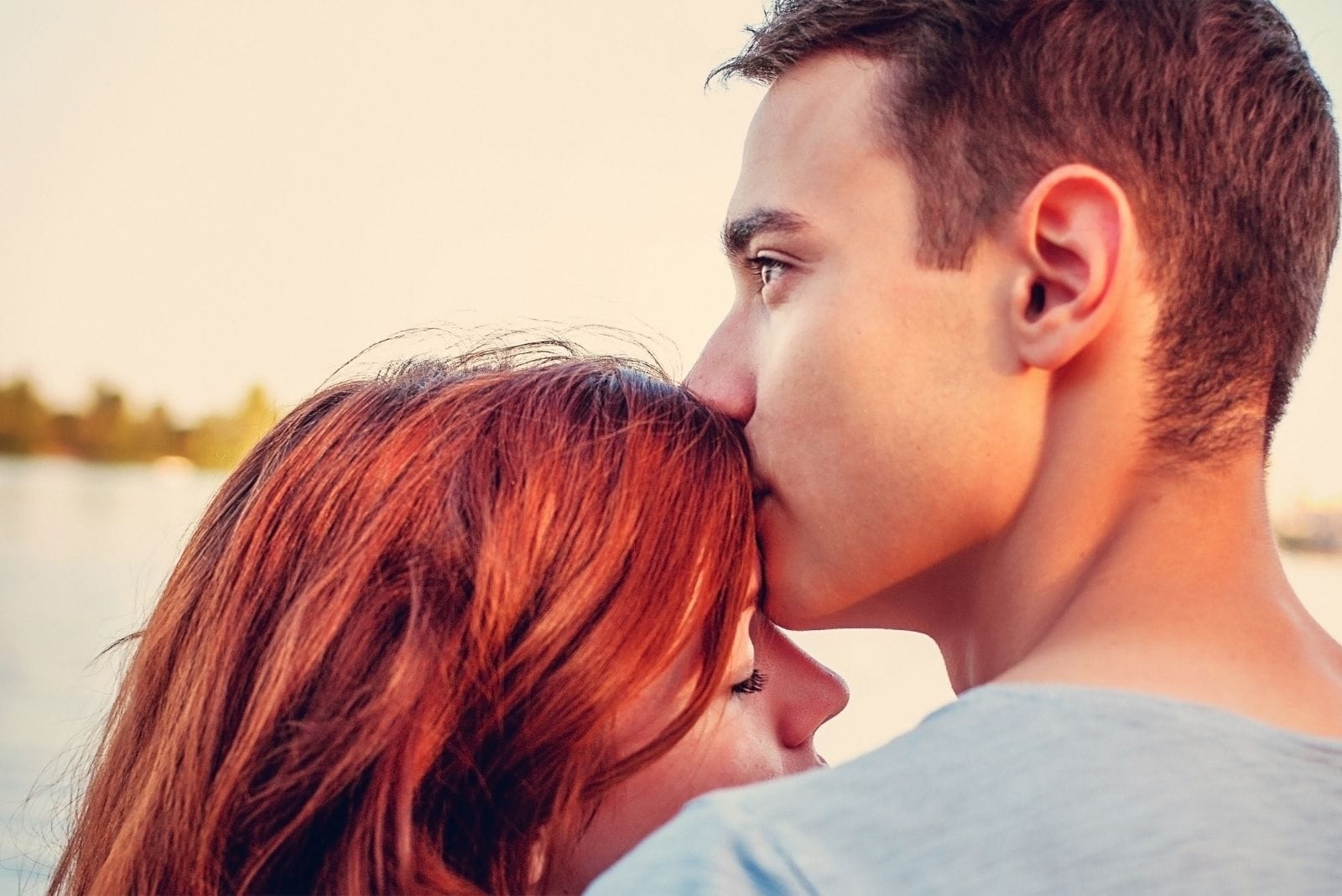 sweet kind man kissing the forehead of his girlfriend in the beach 