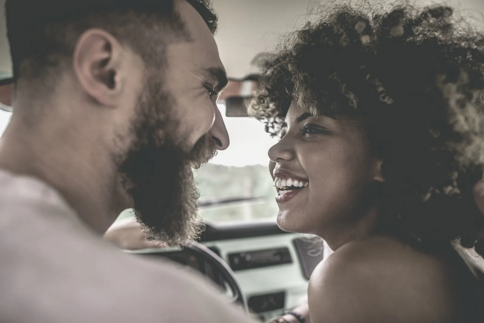 sweet young couple looking eye to eye while inside the car driving
