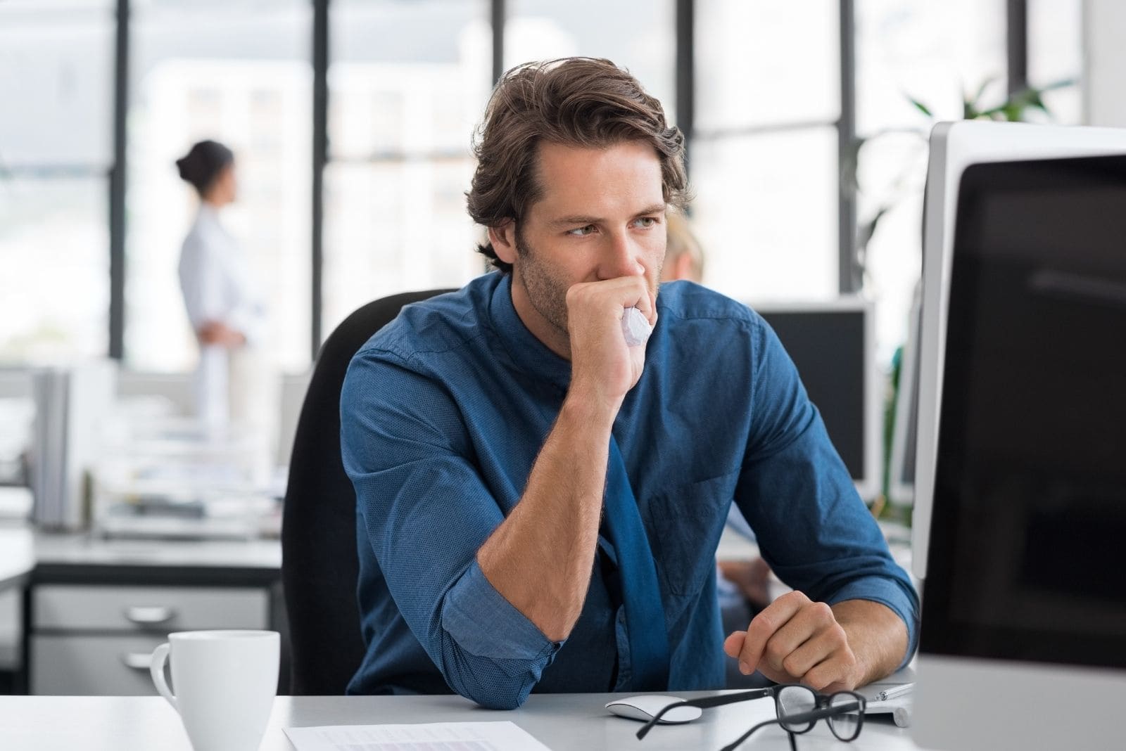 hombre de negocios cansado y estresado sentado junto a la mesa de su oficina mirando el monitor y sosteniendo una pelota antiestrés
