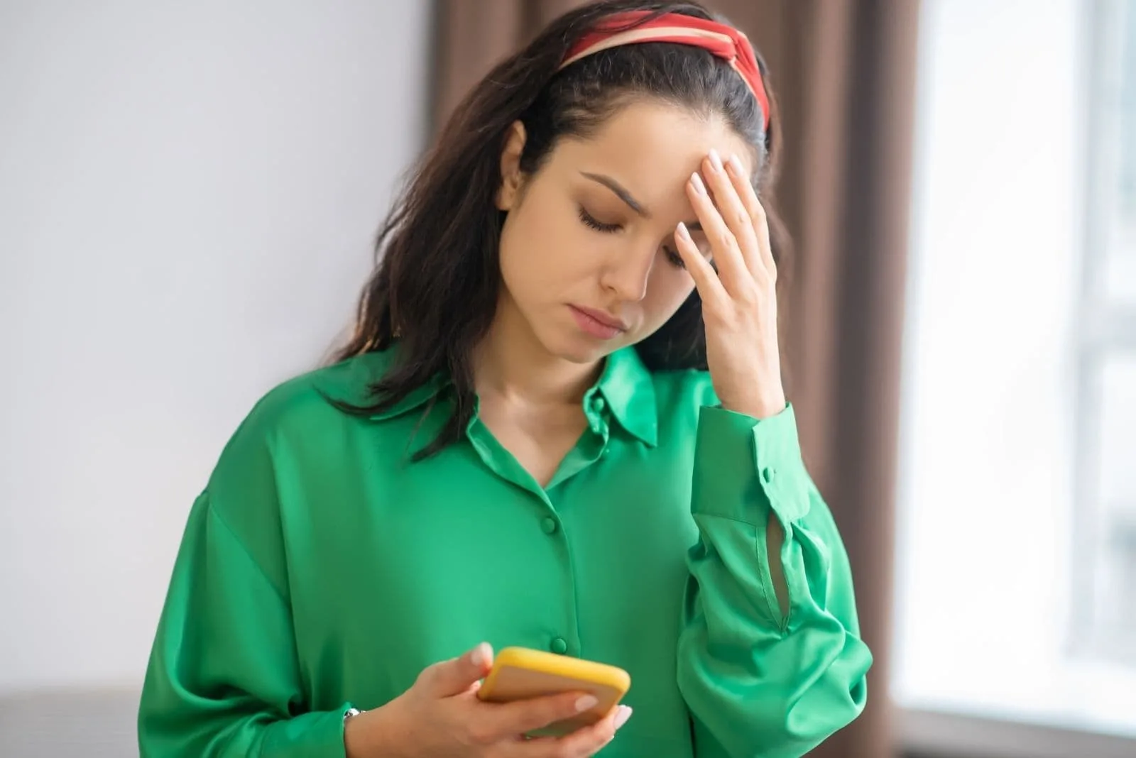 upset woman looking at the smartphone while standing inside home