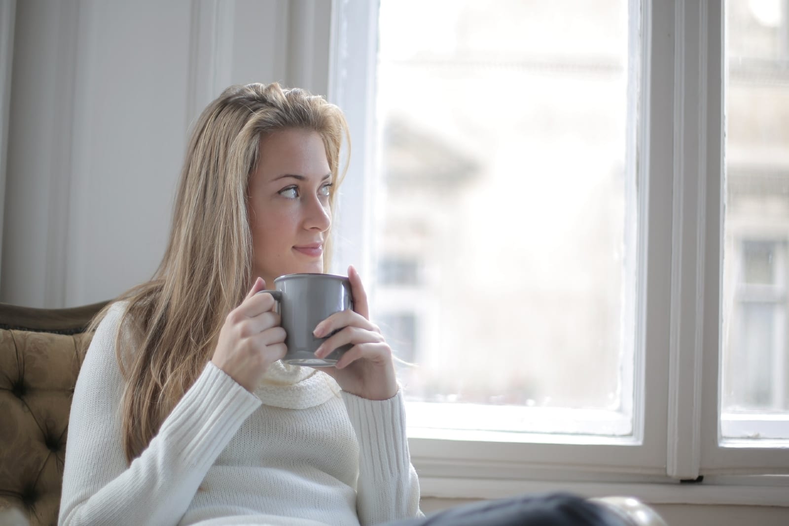 woman drinking coffee while sitting near window