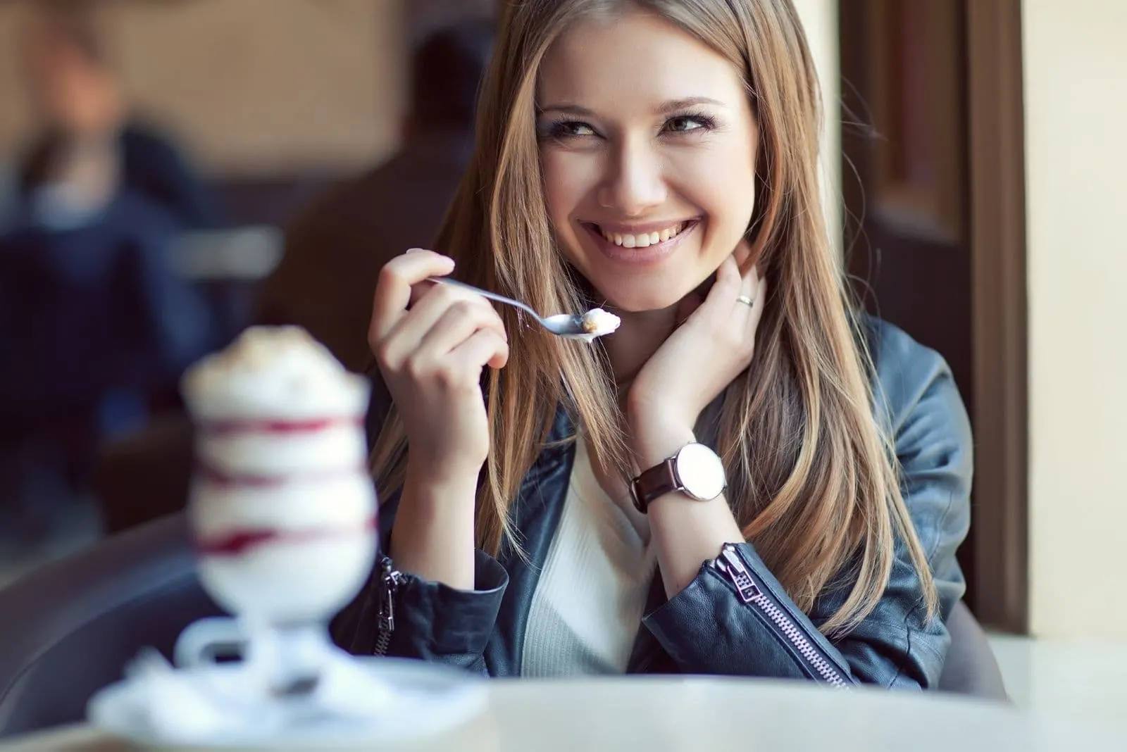 woman eating ice cream and smiling while looking at somebody and holding her hair