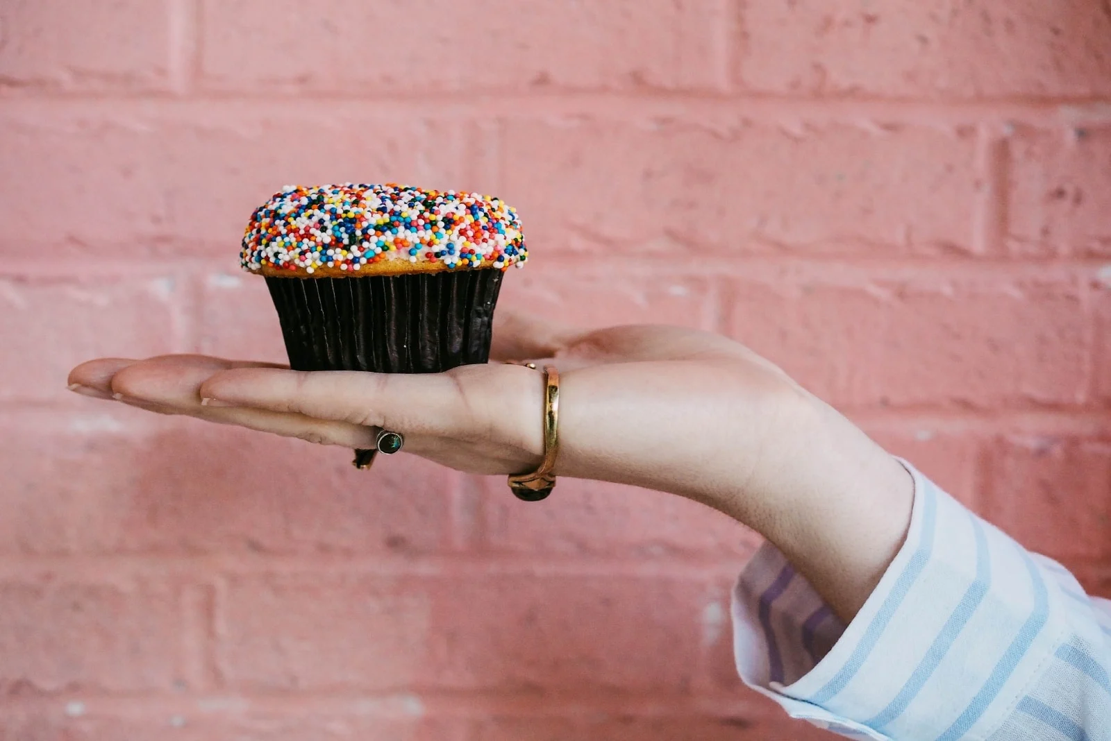 woman holding cupcake while standing near wall