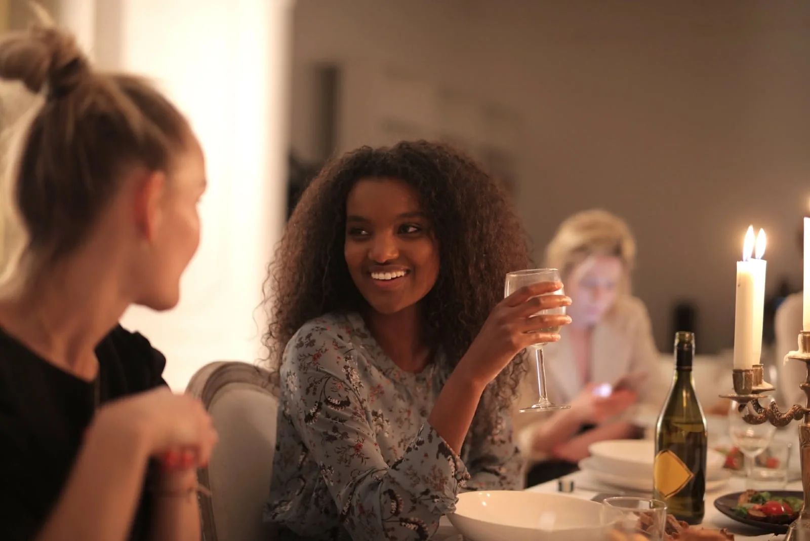 woman holding glass of wine while looking at woman