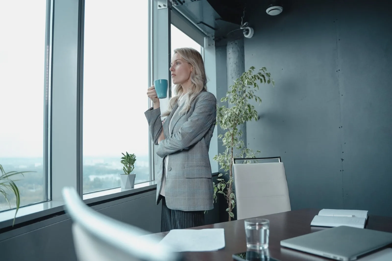 business woman holding blue mug while standing near window