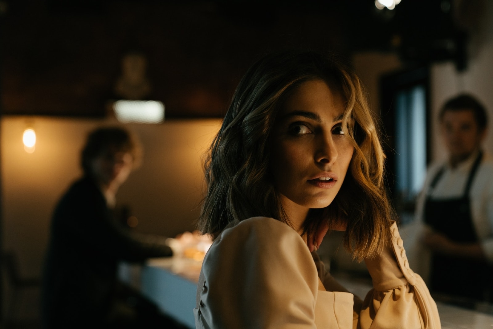 woman in beige dress leaning on bar counter