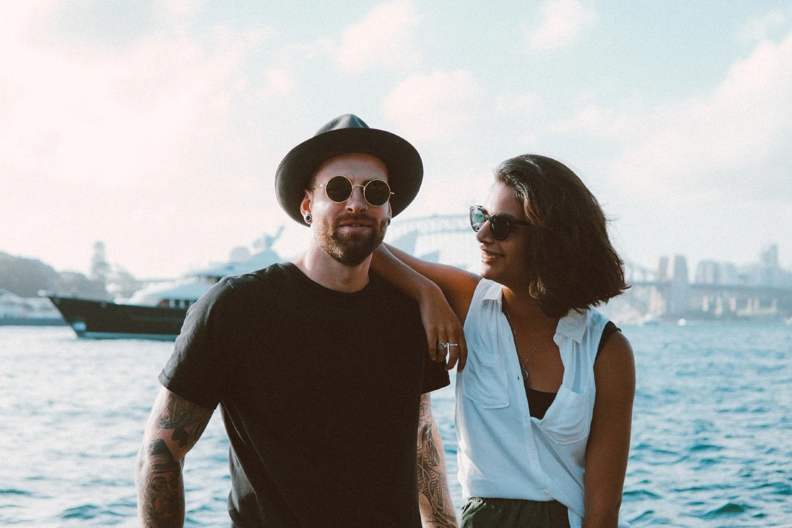 woman leaning on man's shoulder while standing near water