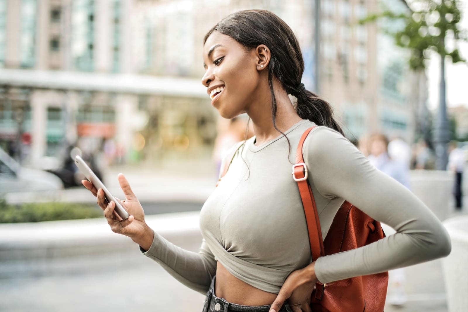 donna felice che guarda il telefono in piedi all'aperto