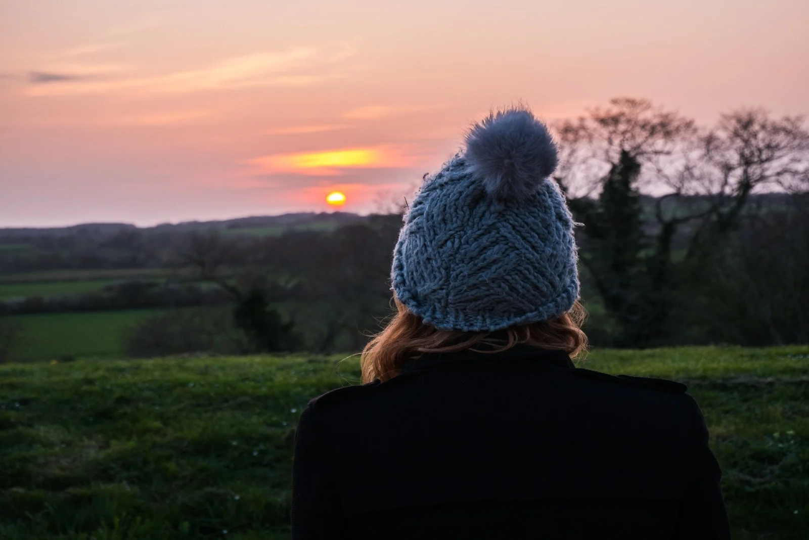 woman in blue knit cap looking at sunset