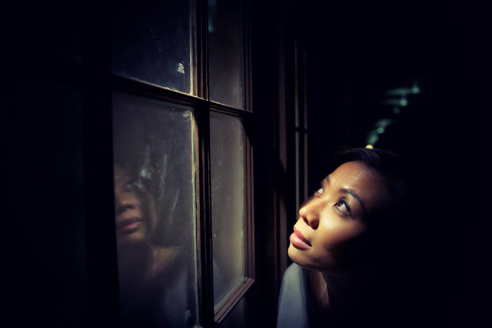 woman looking through window at night