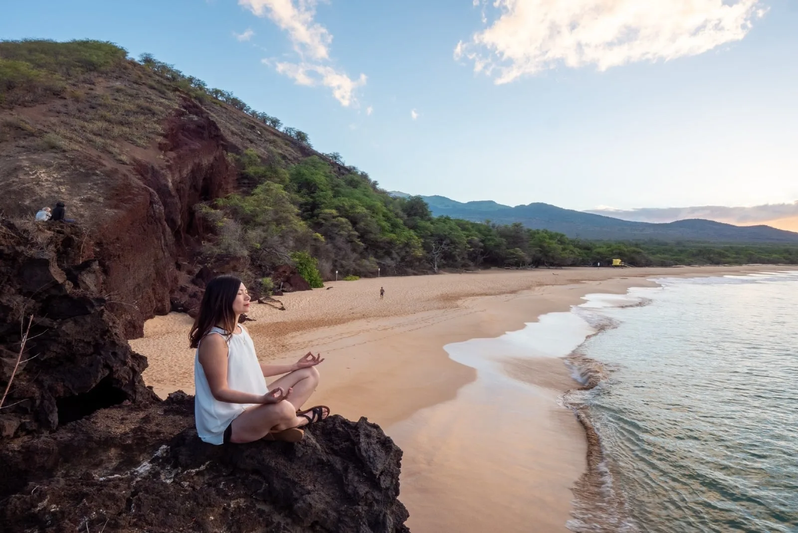 woman meditating while sitting on rock