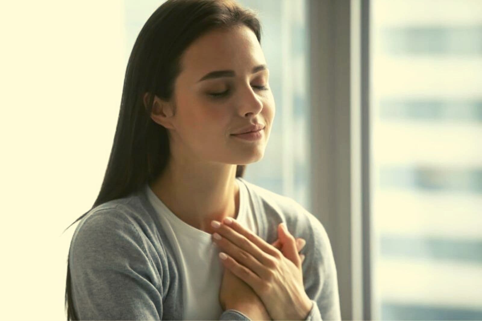 woman putting her hands close to her heart and closing her eyes