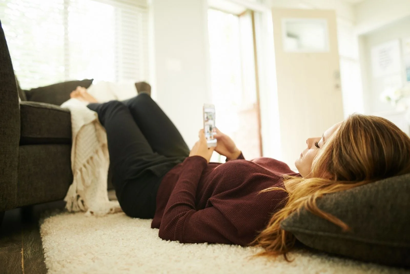 woman relaxing at home lying down and checking her phone