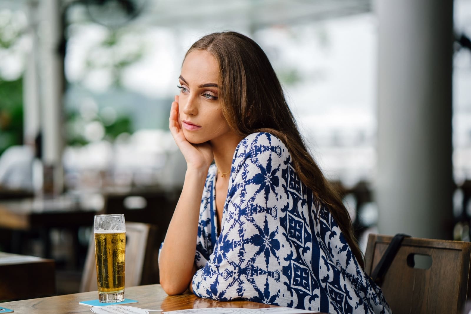 pensive woman in white and blue top sitting at table