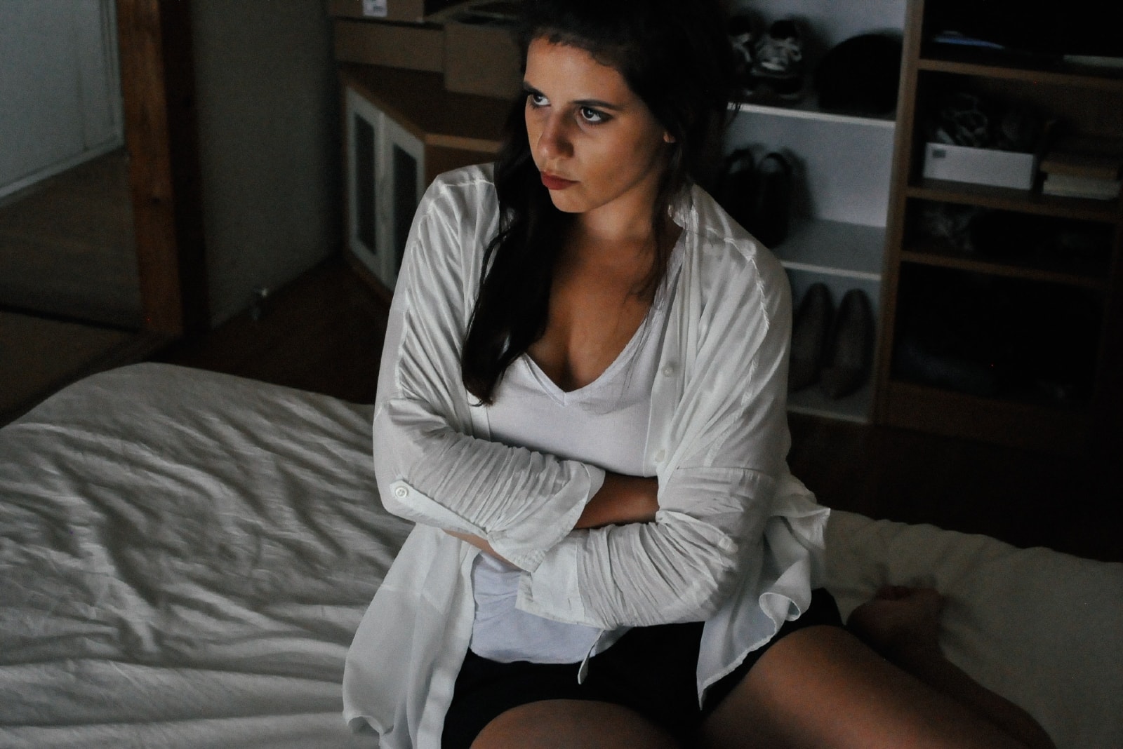 angry woman in white shirt sitting on bed