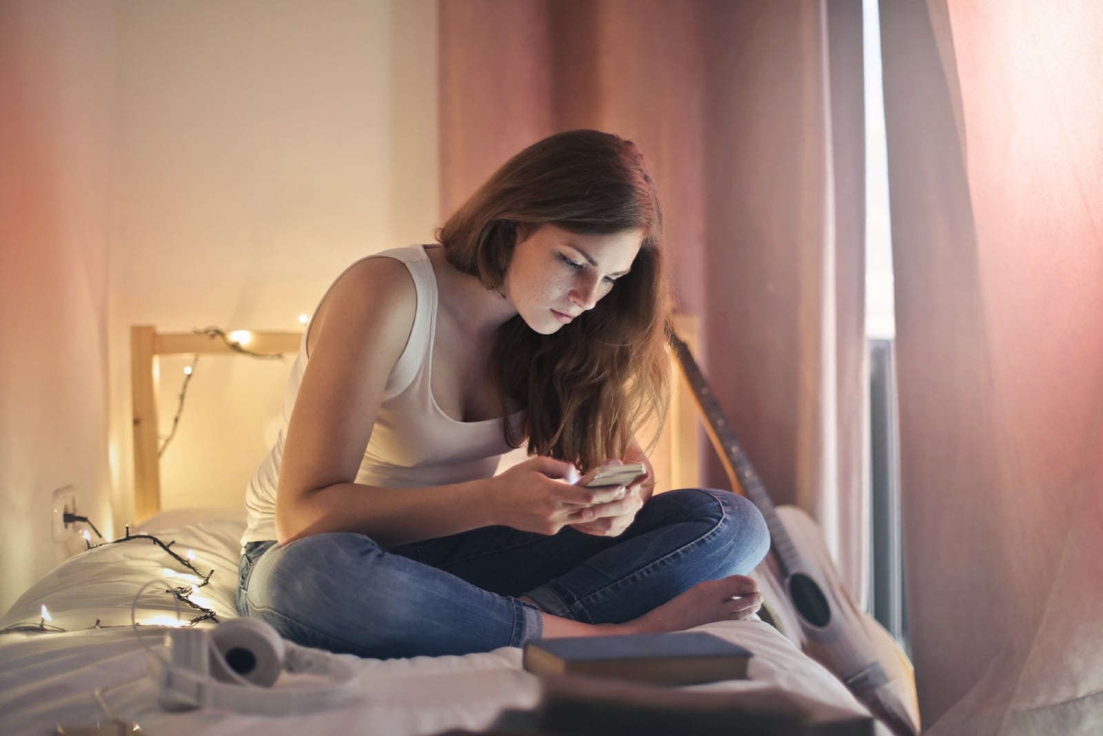 woman using phone while sitting on bed