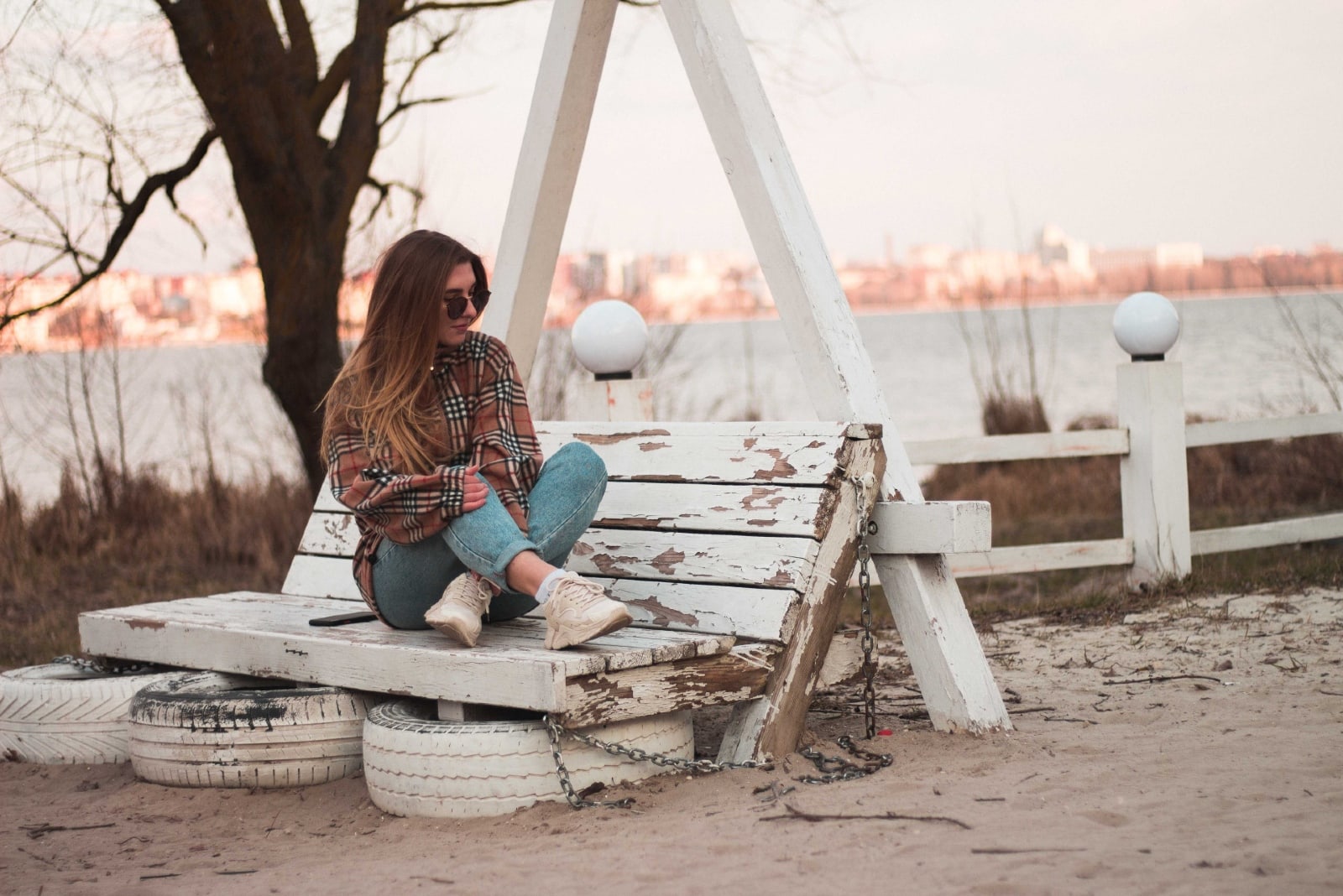 donna con occhiali da sole seduta su una panchina di legno bianca