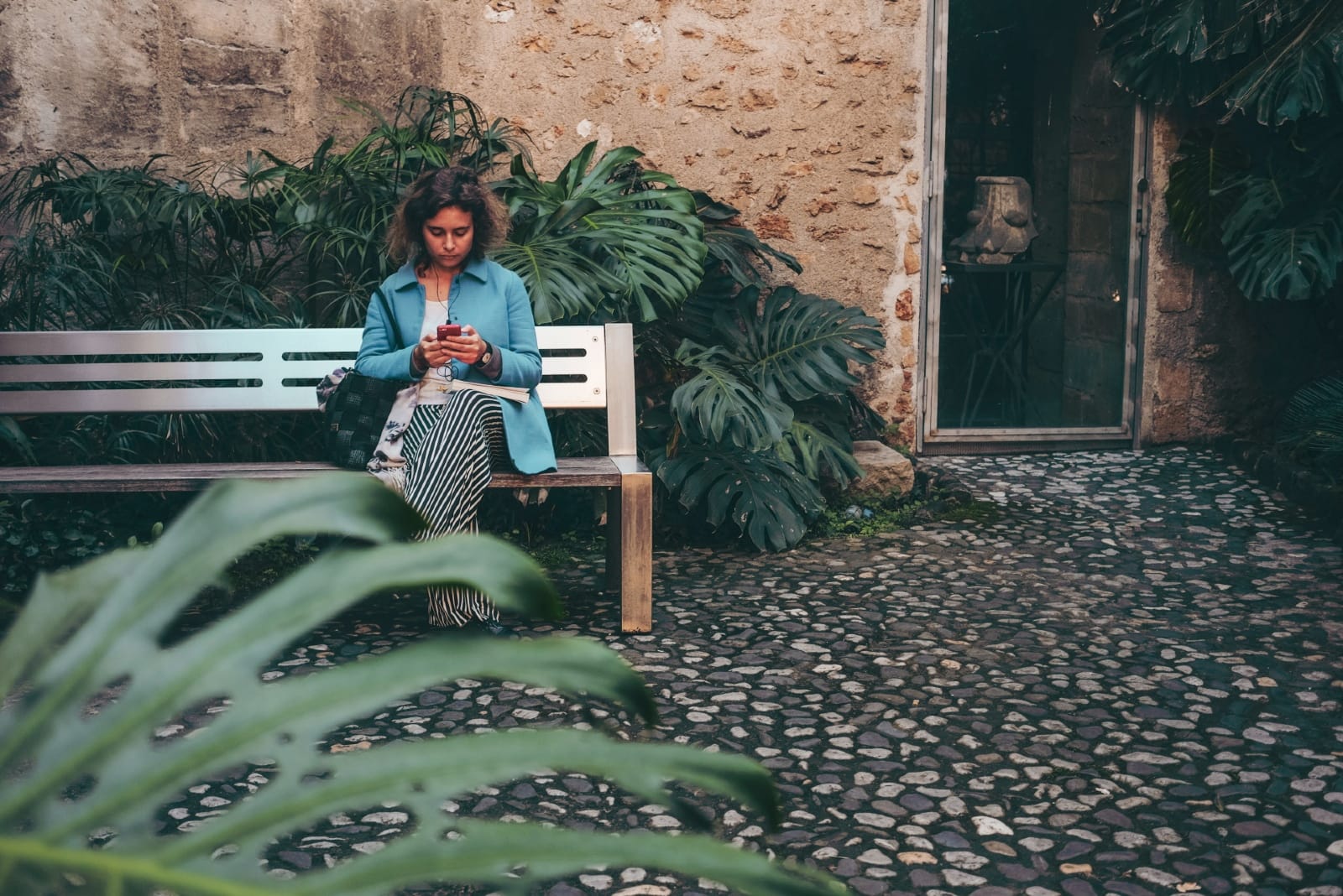 woman using smartphone while sitting on bench