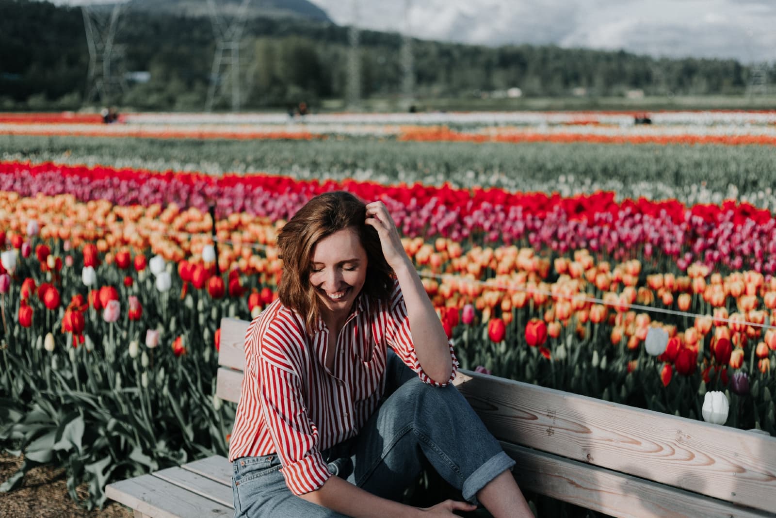 donna felice seduta su una panchina vicino a un campo di tulipani