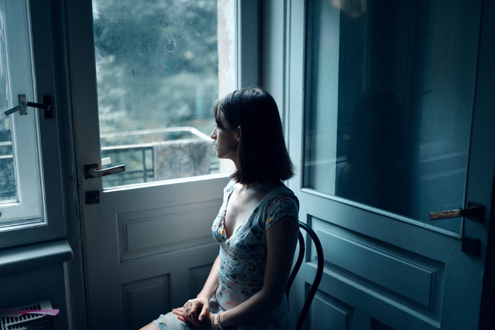 donna in abito stampato seduta su una sedia vicino alla porta