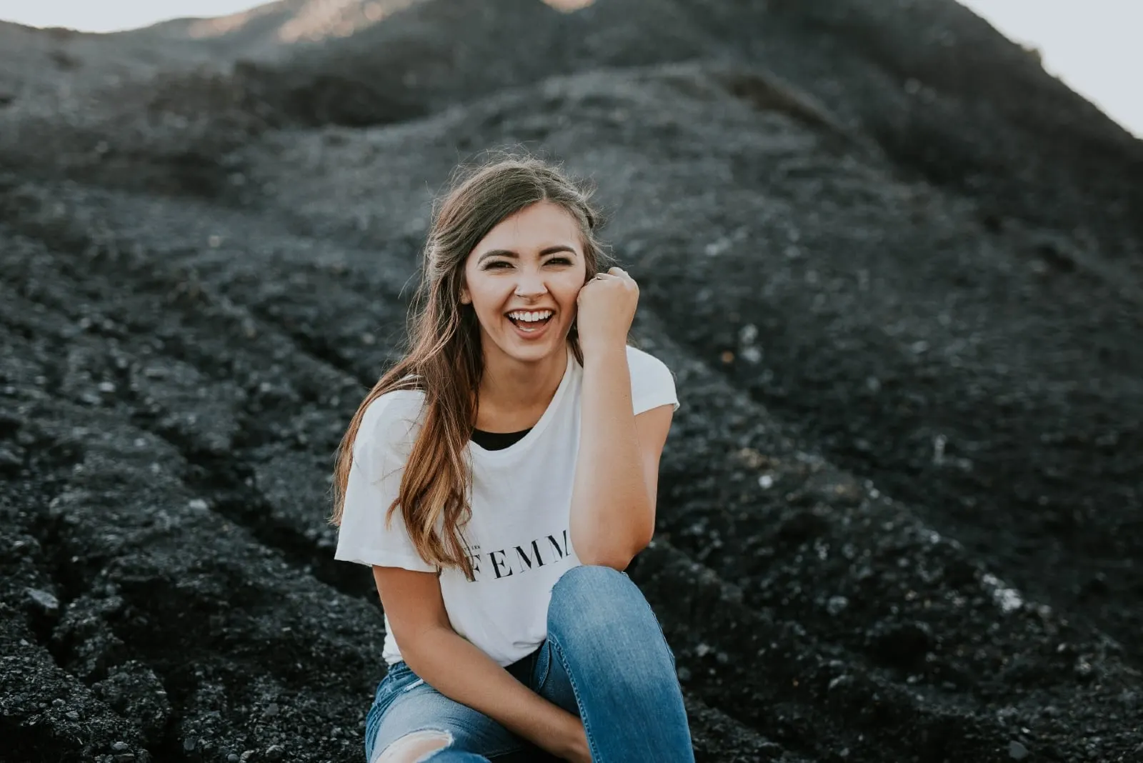 woman in white t-shirt laughing while sitting on ground