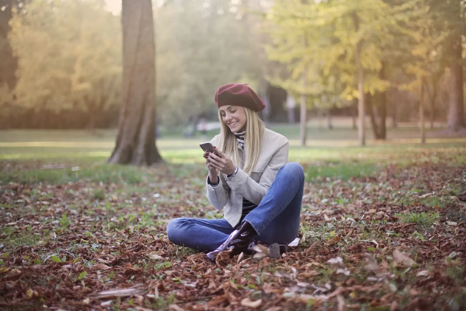 woman looking at phone while sitting on ground