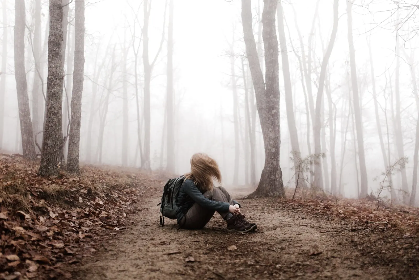 woman sitting on ground in forest
