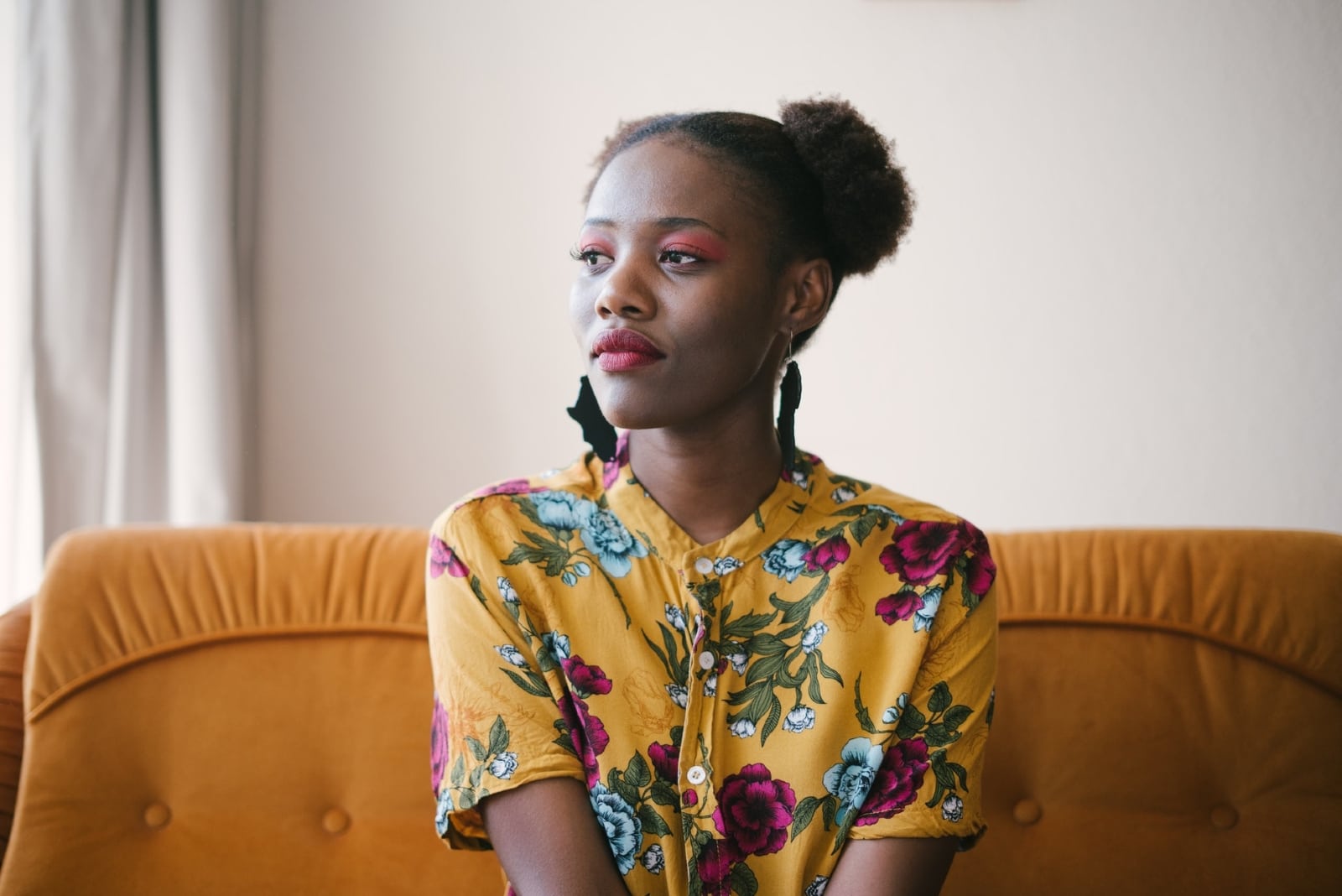 woman in floral top sitting on yellow sofa