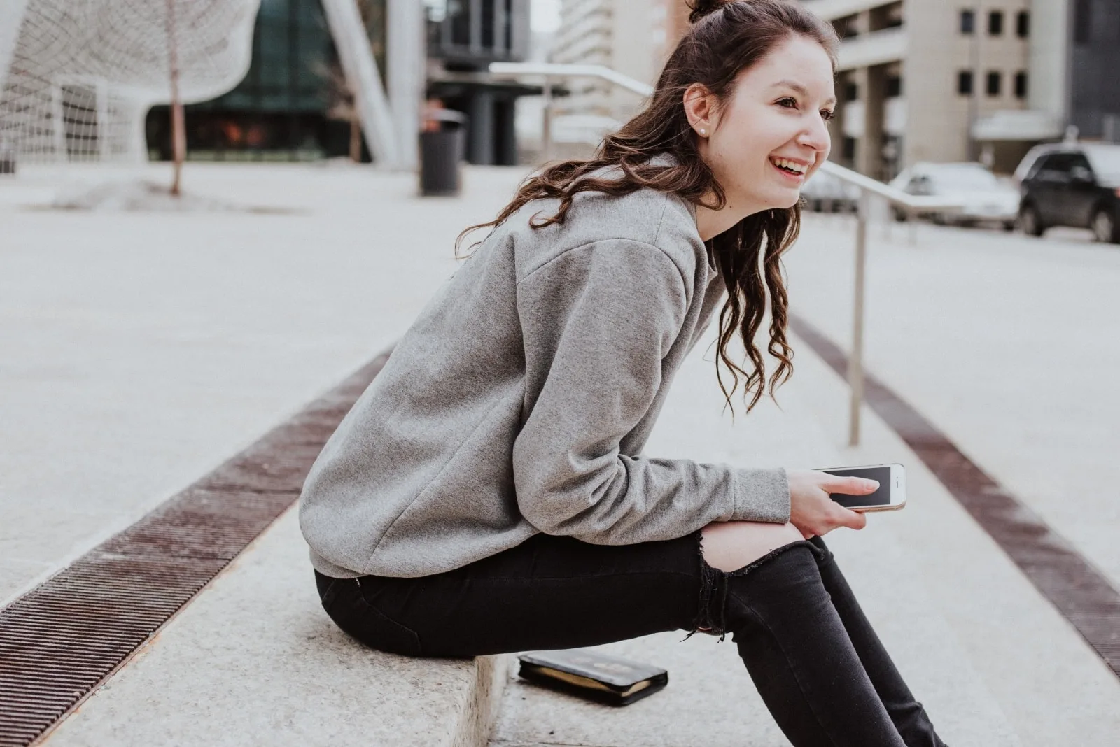 woman in gray sweatshirt sitting on stairs smiling