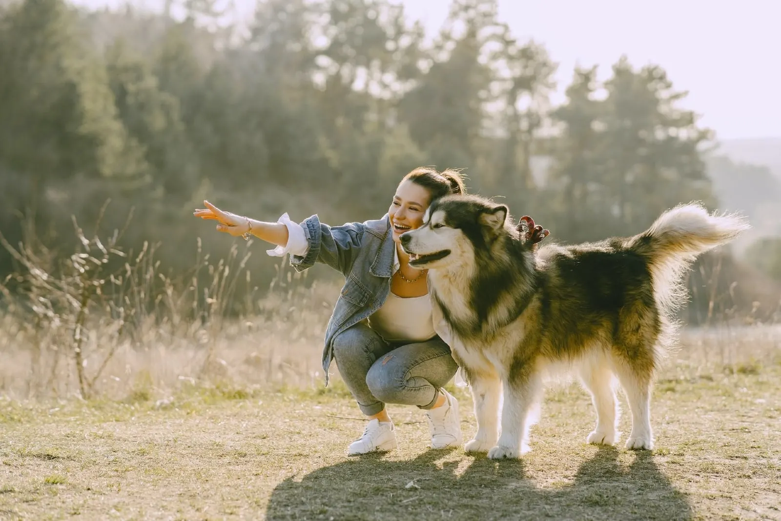 woman in denim jacket smiling near dog