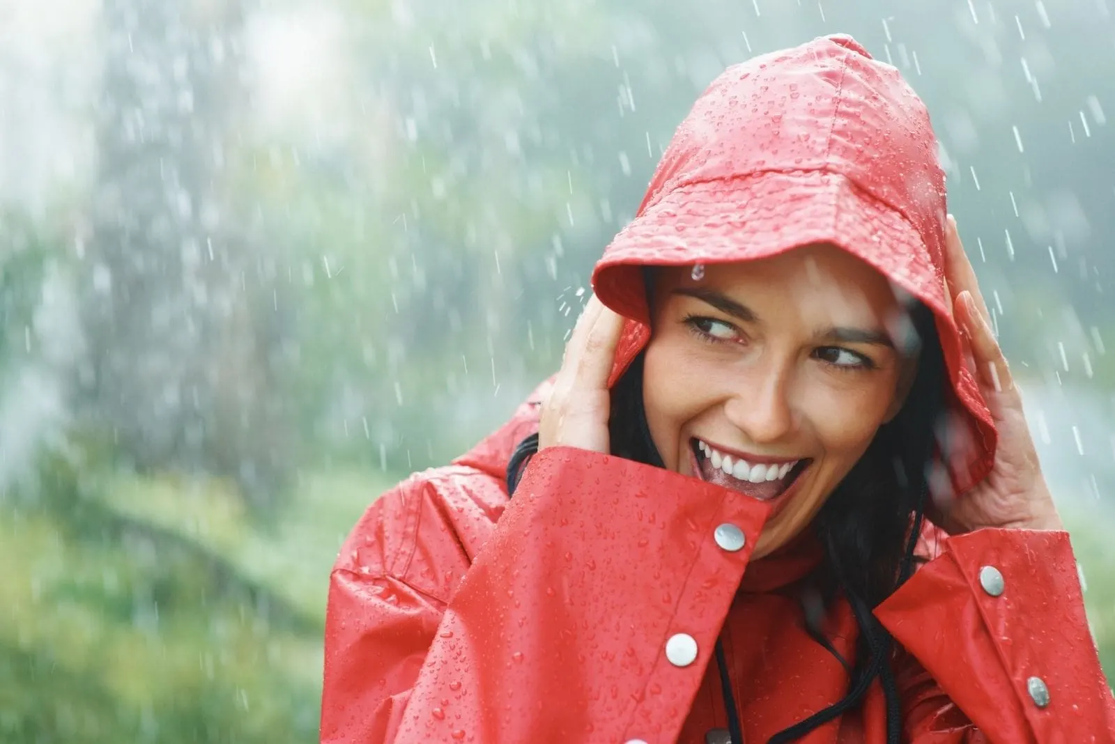 woman smiling white out in the rain wearing raincoat