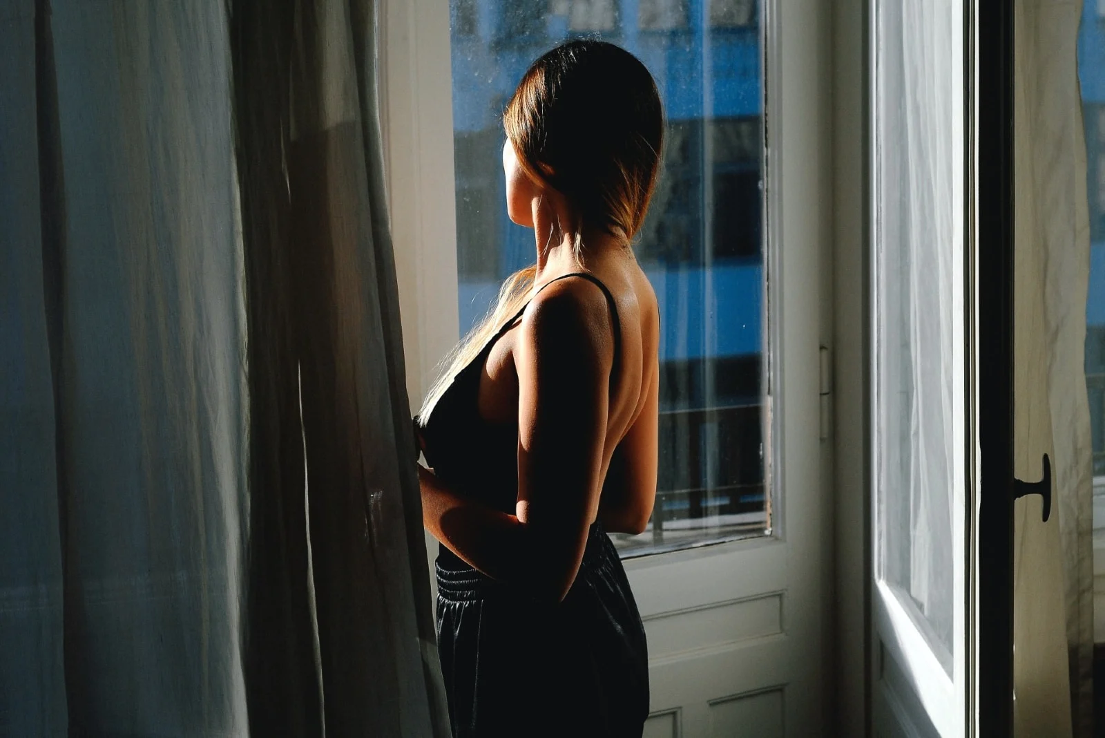 woman in black top standing near door looking outside