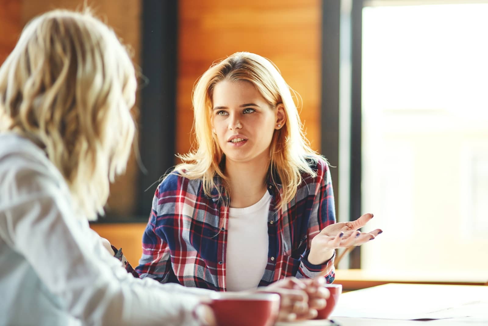 blonde woman talking to woman while sitting at table